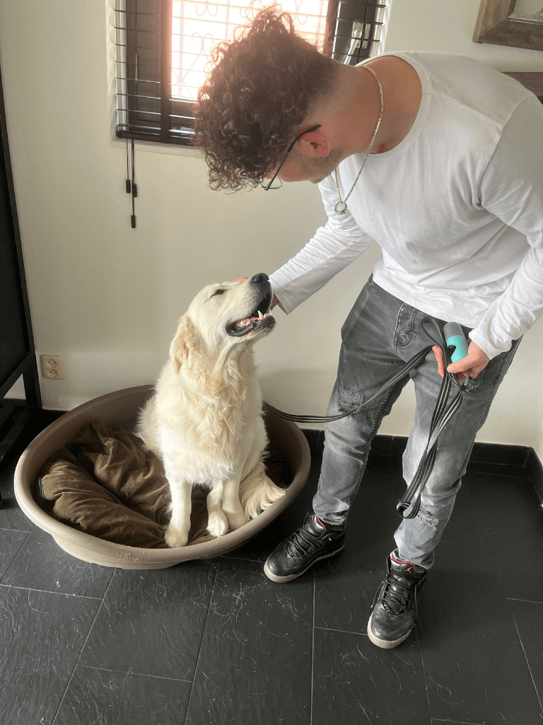Foto van Emre (oprichter) met Tobi, een golden retriever. Emre aait Tobi